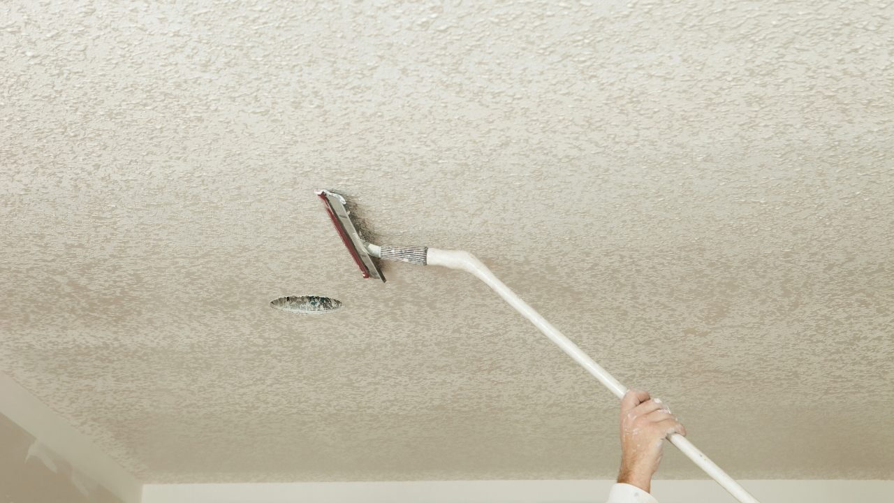 Person using a pole sander to smooth a textured ceiling.
