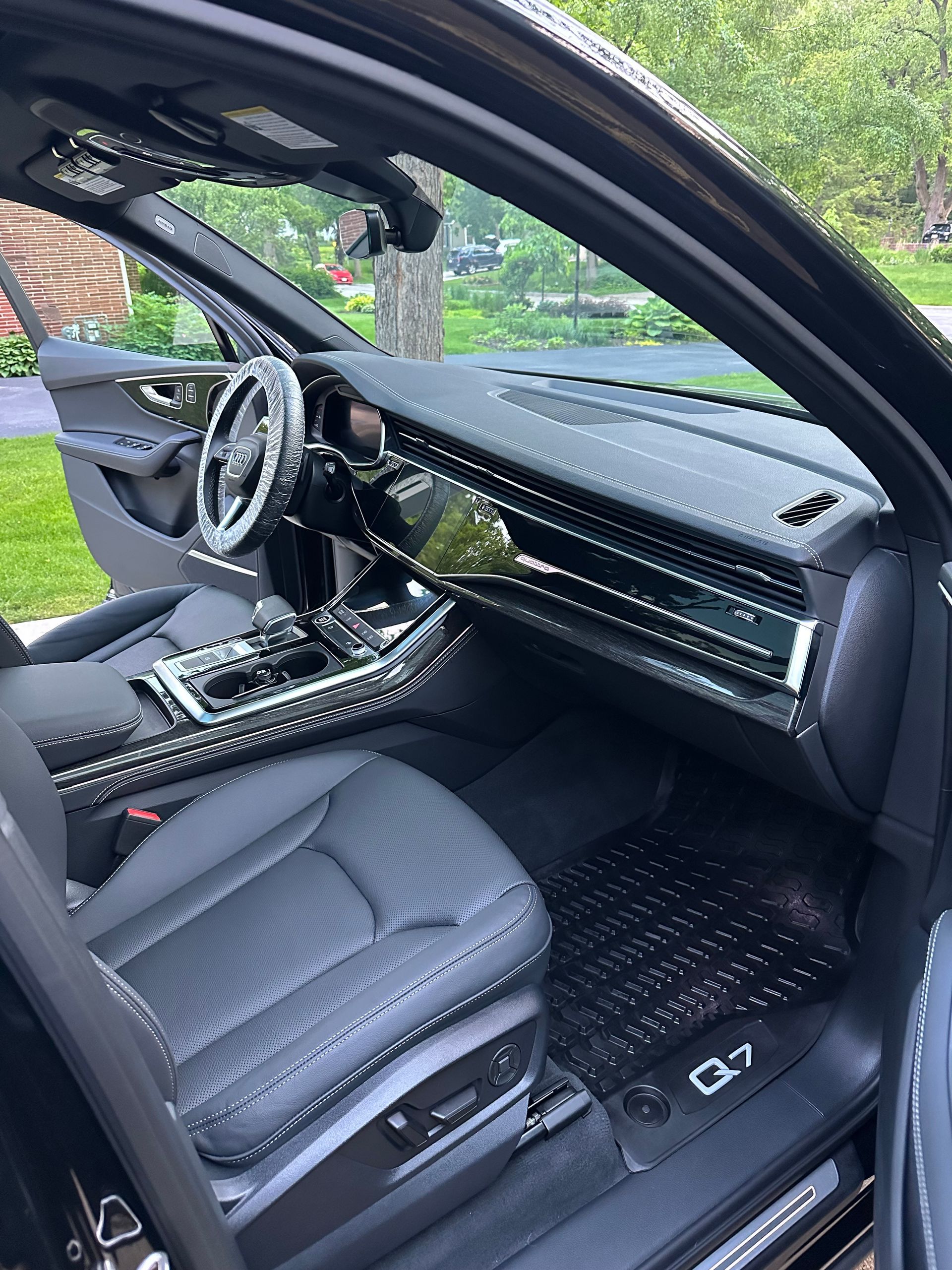 Luxury car interior with black leather seats, dashboard, and open driver’s door.