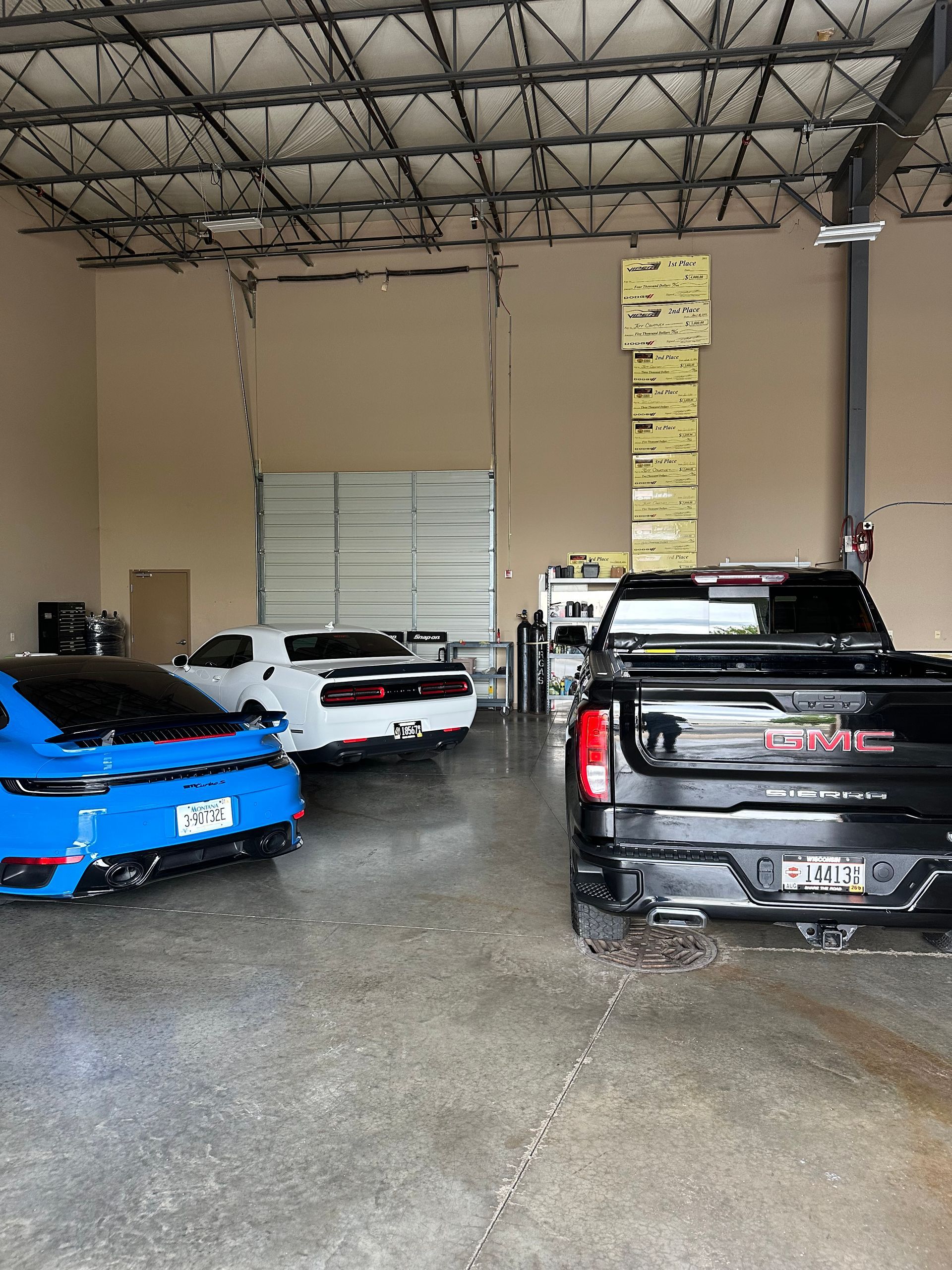 Cars parked inside a warehouse with high ceilings and stacked boxes on a back wall