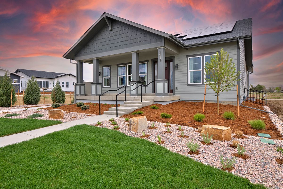 A house with a lush green lawn and a sunset in the background.