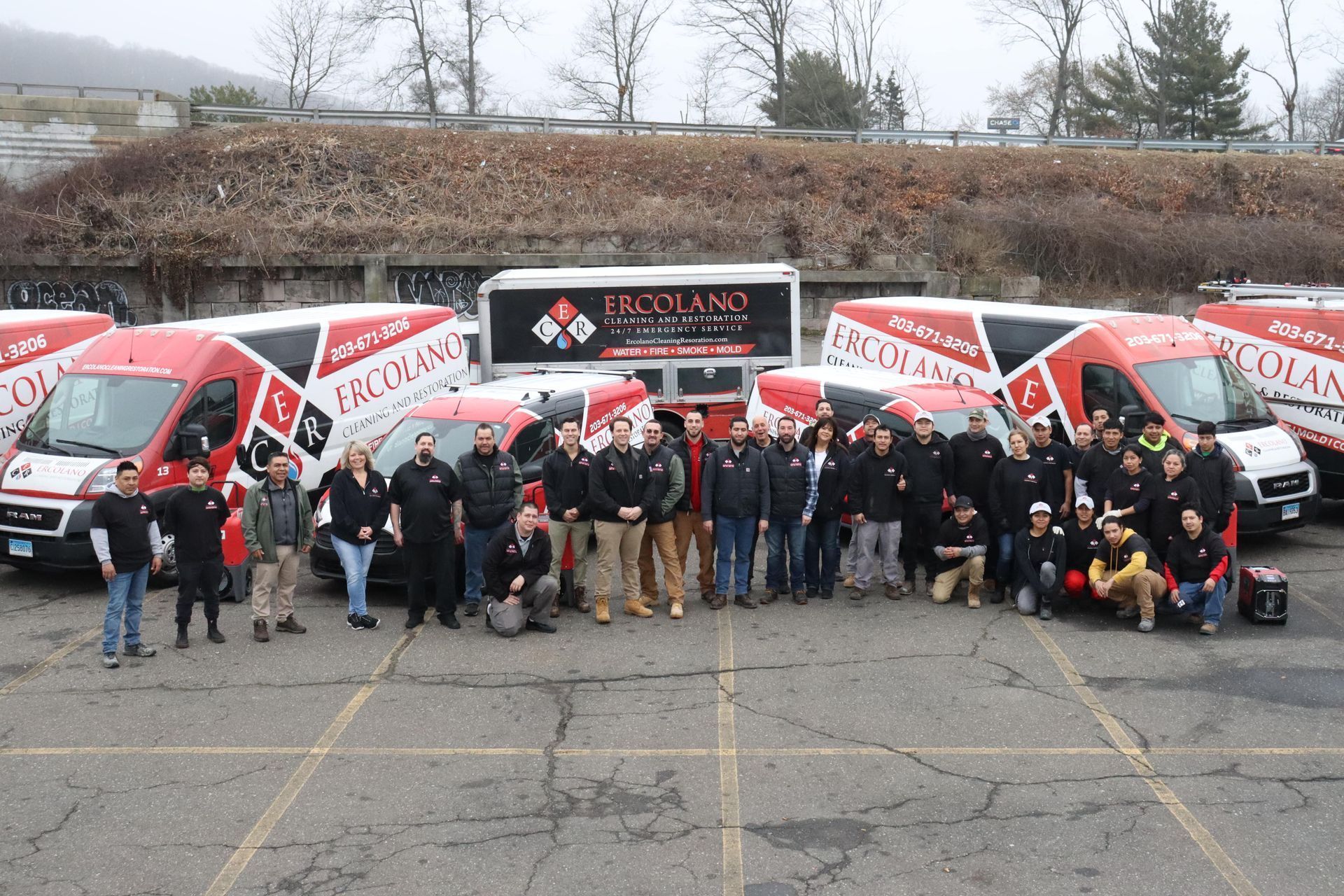 A group of people are posing for a picture in front of a row of vans.