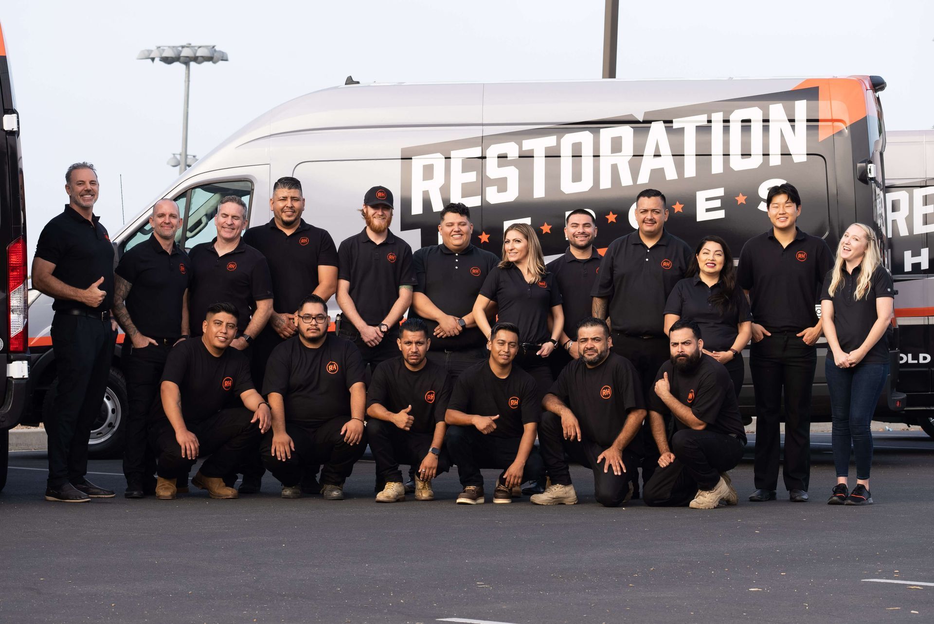A group of people are posing for a picture in front of a restoration van.