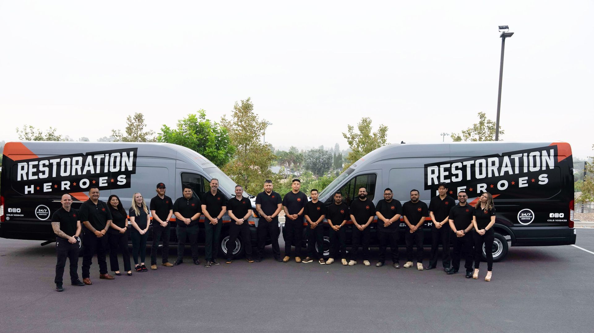 A group of people standing in front of two restoration heroes vans.