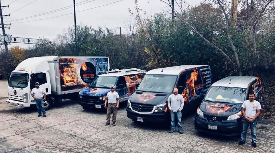 A group of men are standing in front of a row of trucks and vans.