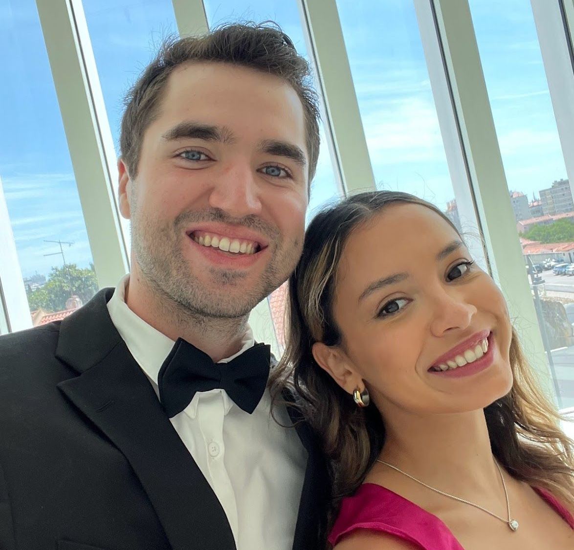 A man in a tuxedo and bow tie is standing next to a woman in a pink dress