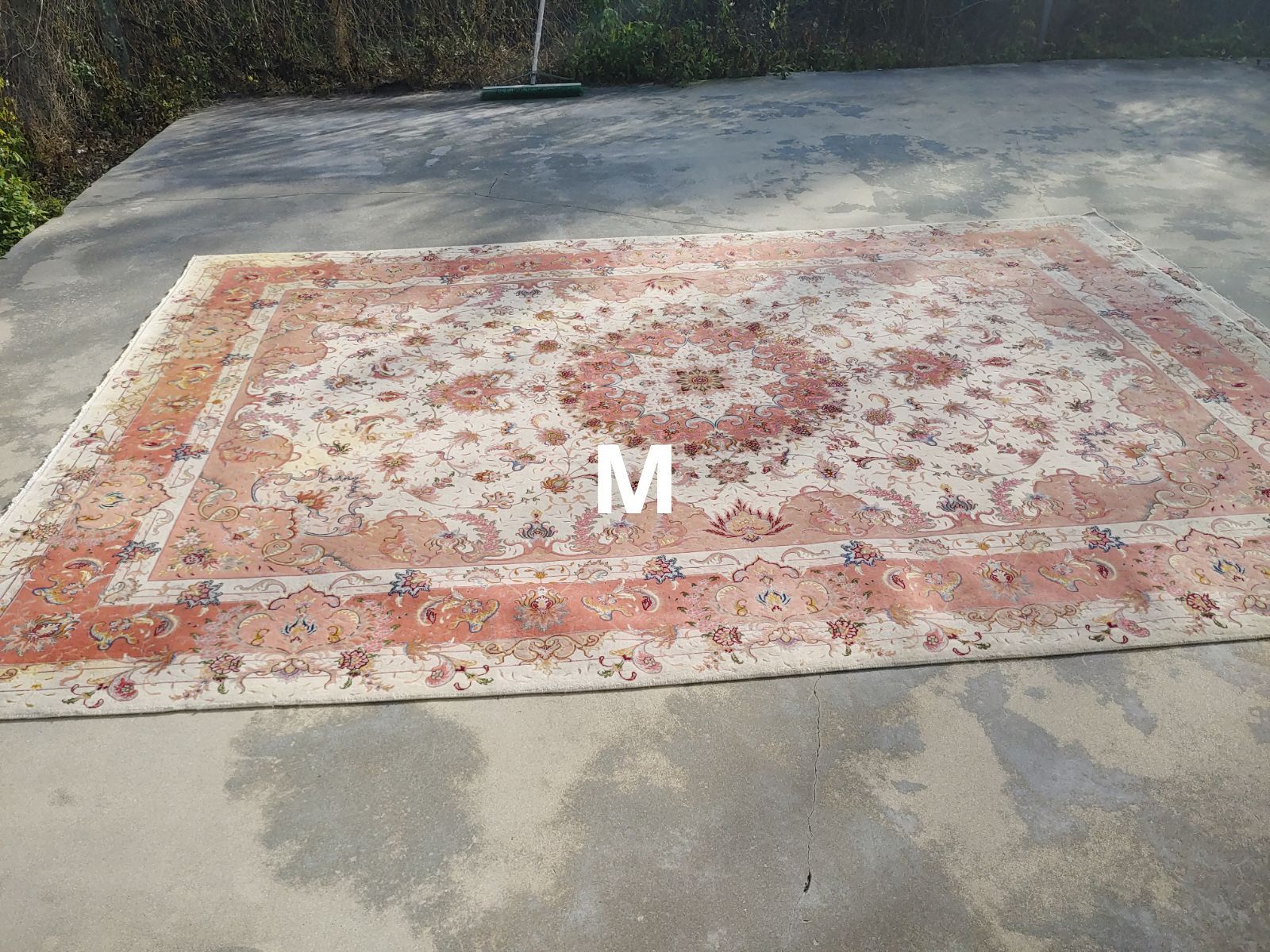 Rug with cream and peach floral pattern on concrete surface.