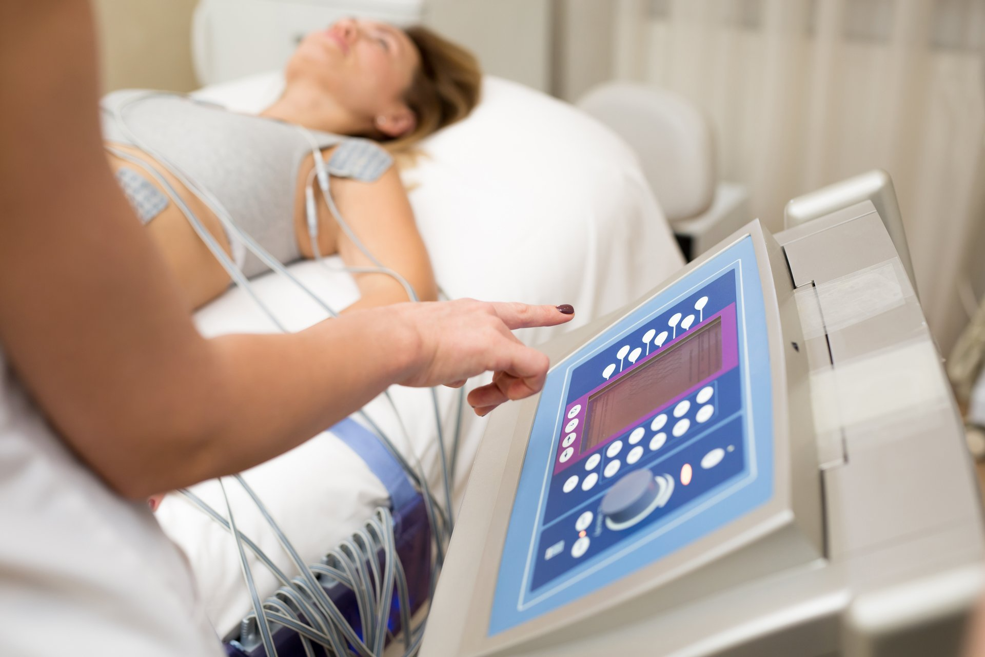 Eine Frau liegt mit einer Maschine auf ihrem Bauch auf einem Bett.