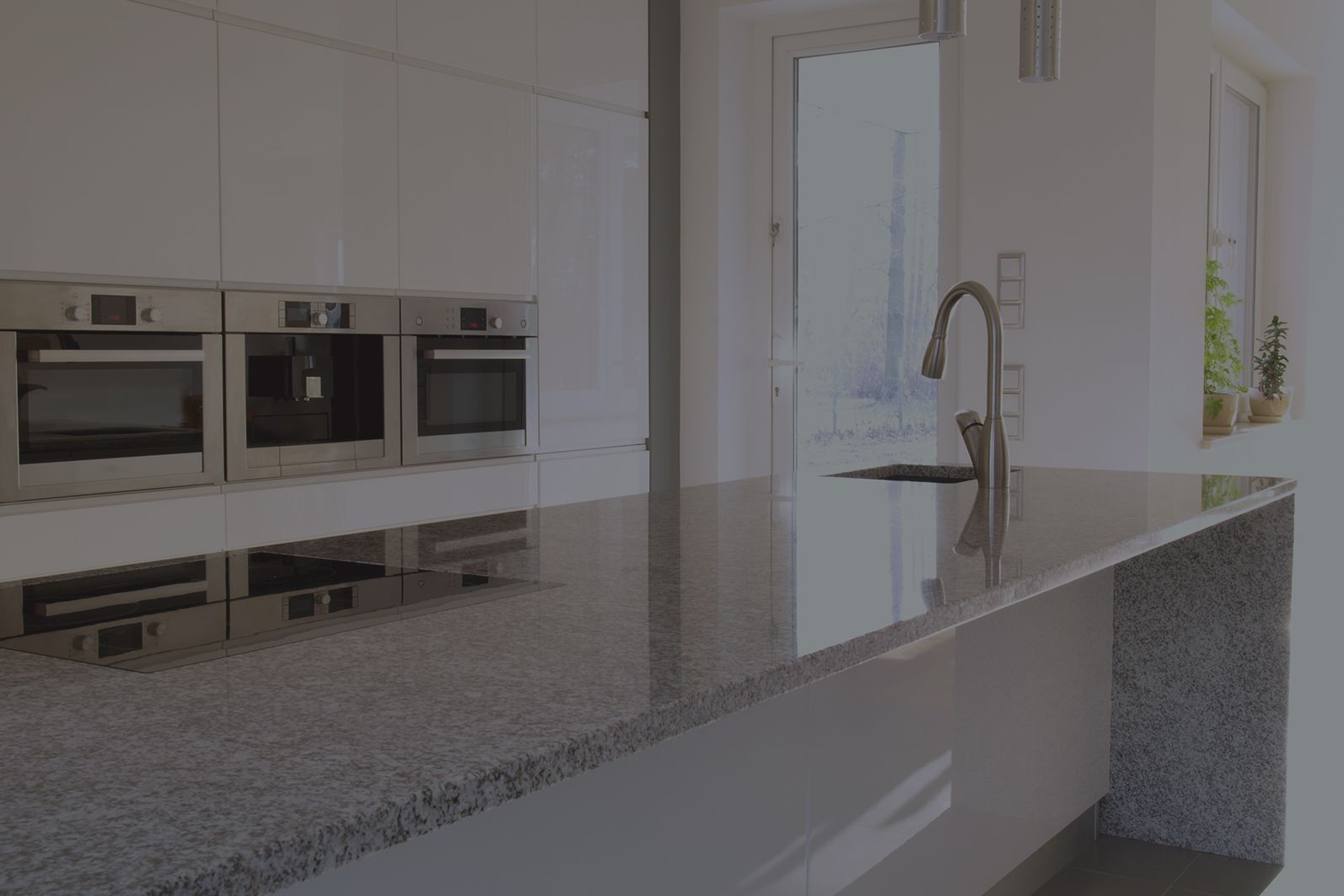 Cuisine blanche moderne avec appareils électroménagers en acier inoxydable et comptoir en granit.