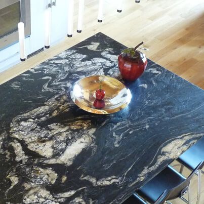 Comptoir en granit foncé avec un bol à fruits et une pomme décorative rouge.