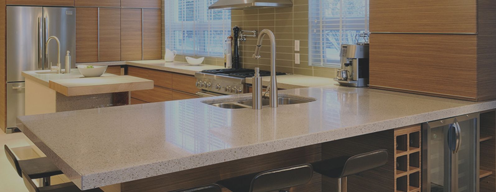 Cuisine moderne avec grand îlot, électroménagers en acier inoxydable et armoires en bois.