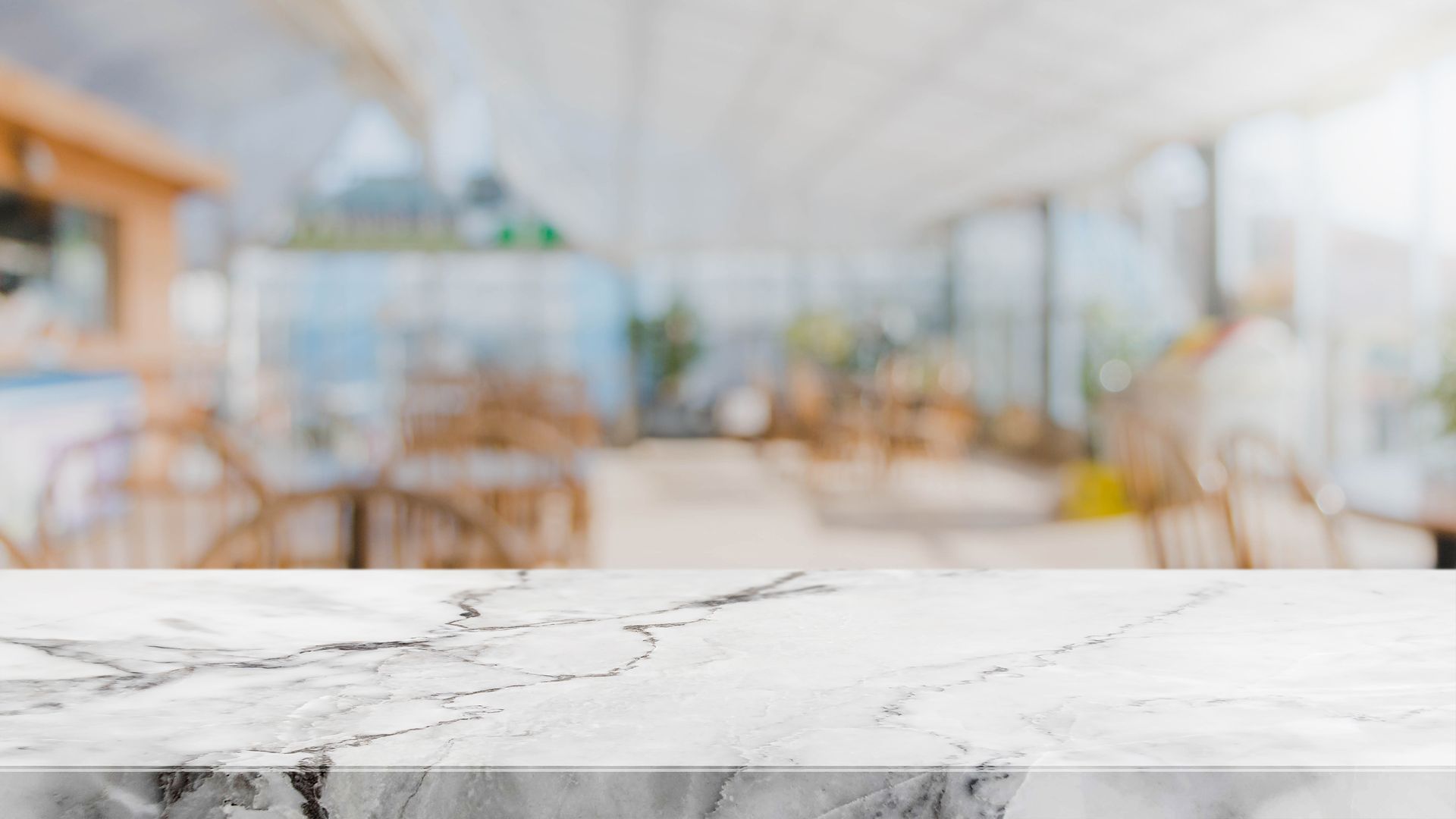 Comptoir en marbre devant un arrière-plan de café flou avec des tables et des fenêtres.