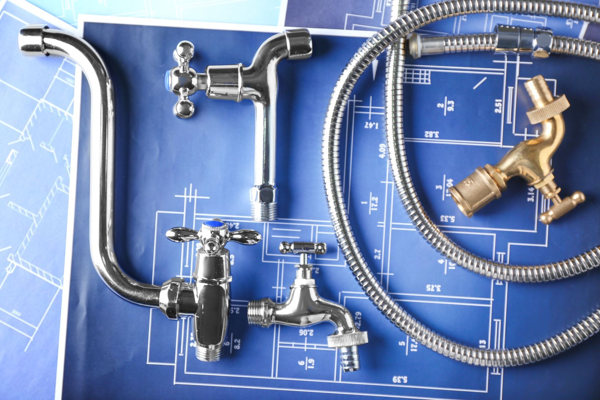 Plumbing fixtures and blueprints demonstrate a plumbing maintenance concept.