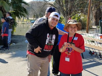 A man and a woman are standing next to each other holding fishing rods.