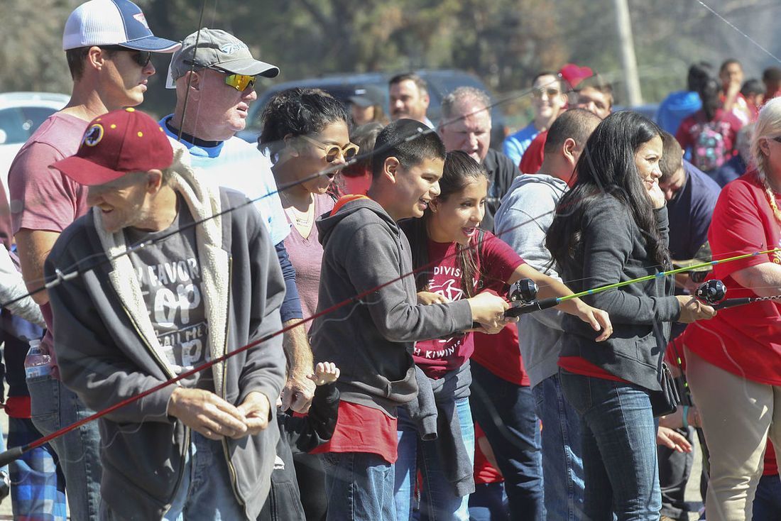 A group of people are standing in a line holding fishing rods.