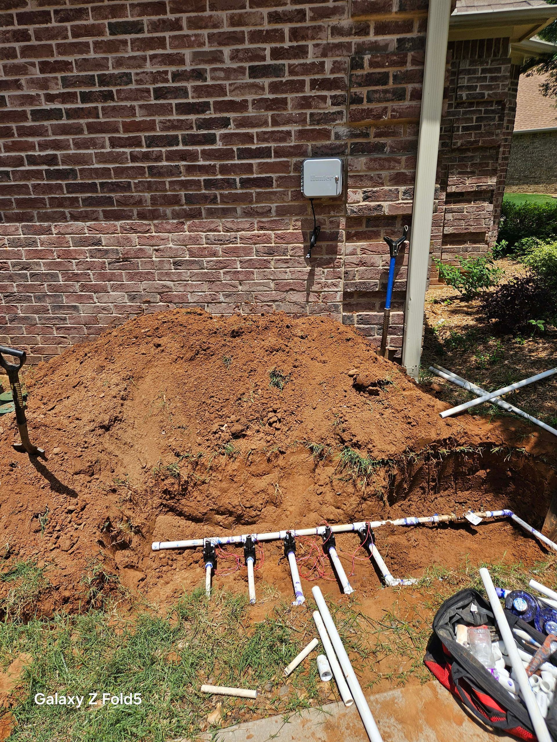A pile of dirt is sitting in front of a brick wall.