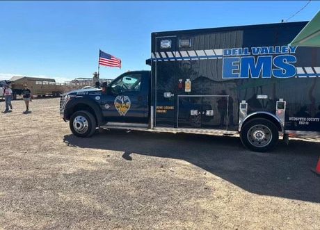 A Dell Valley ambulance is parked in a dirt field