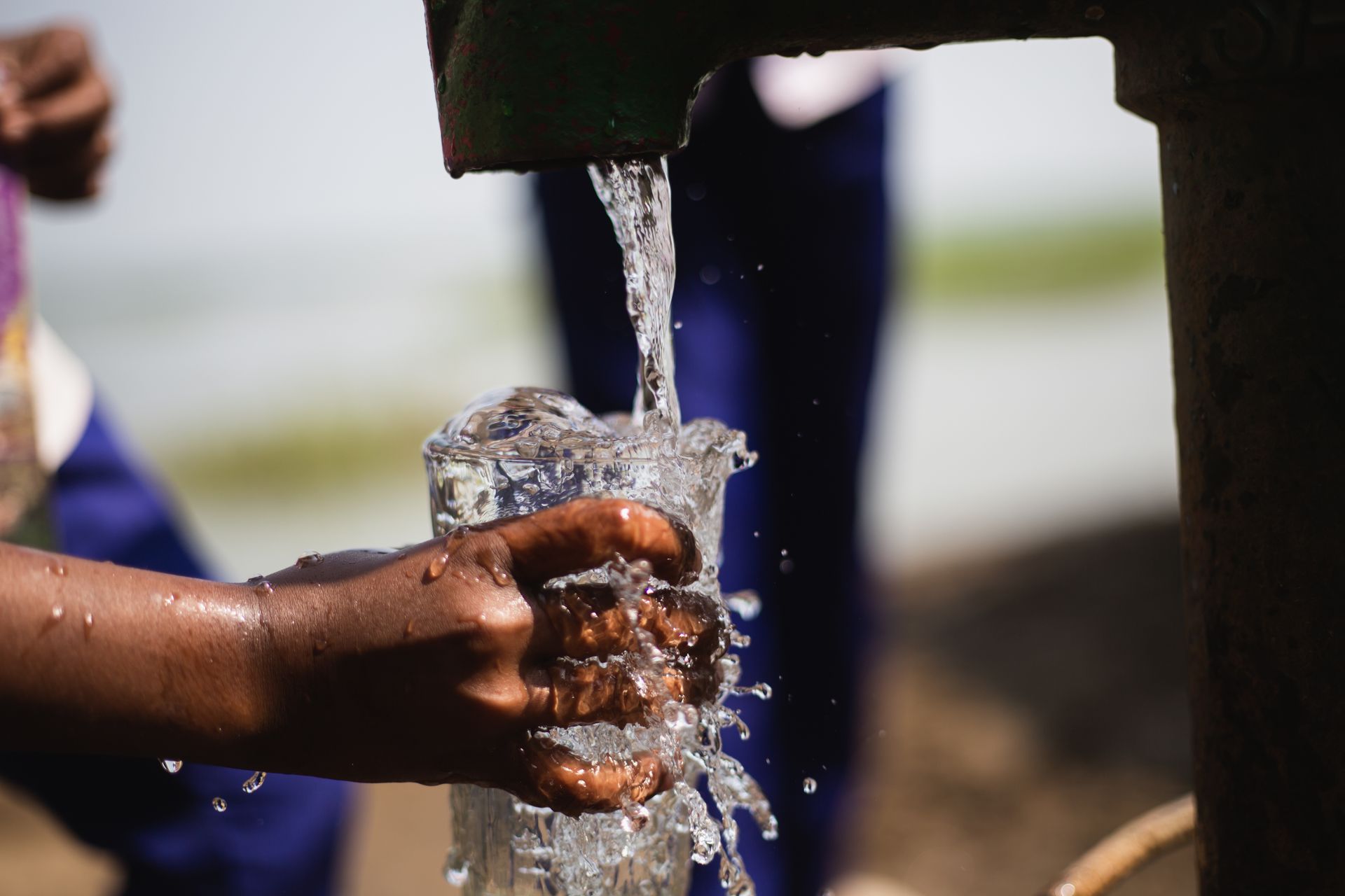 Close-up of a child’s hand as he fills a glass with water from a water pump. Close-up of a child’s hand as he fills a glass with water from a water pump.