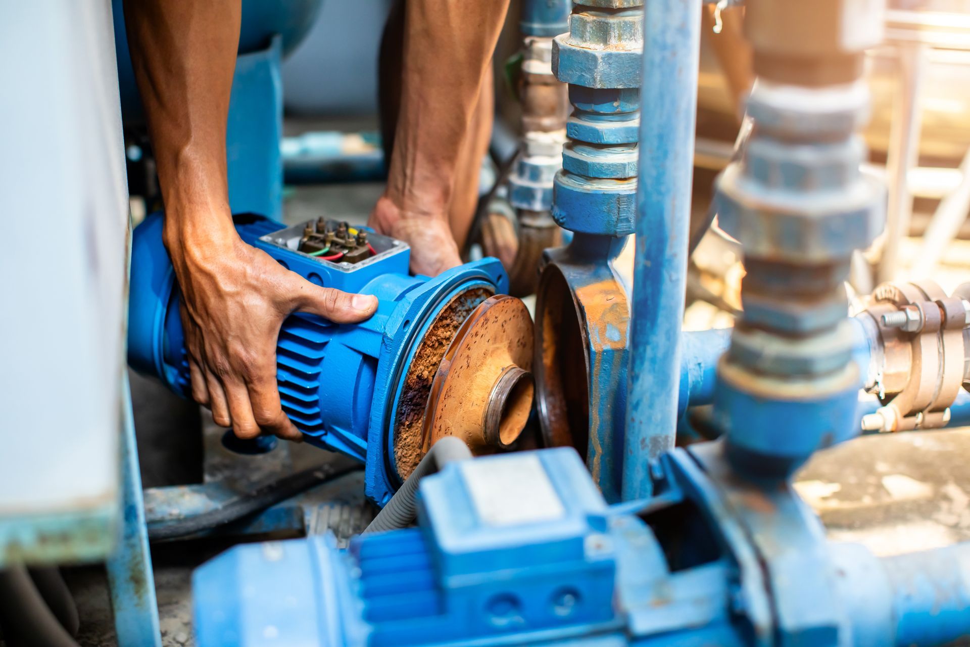 Hands of a plumber repairing and removing the motor of a centrifugal water pump. Hands of a plumber repairing and removing the motor of a centrifugal water pump.