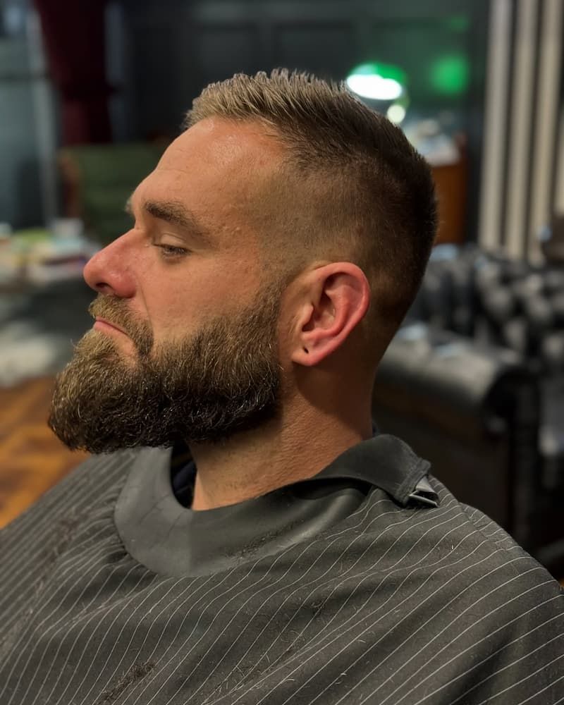 A Man With a Beard is Getting His Hair Cut at a Barber Shop — Connolly & Co Barbers In Robina, QLD