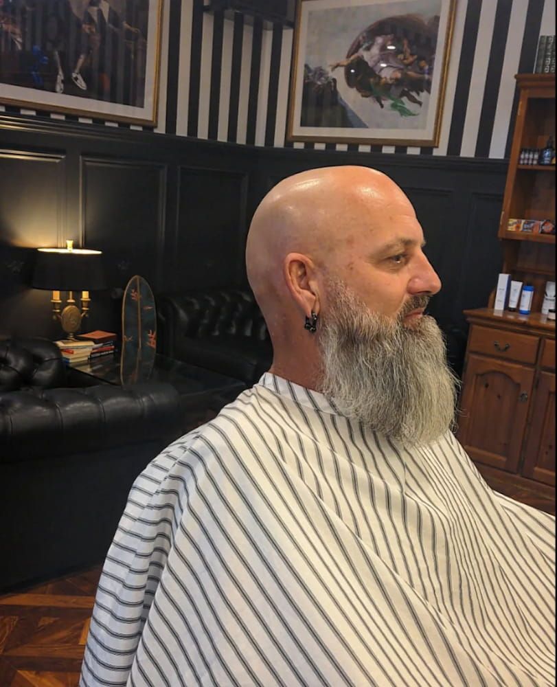A Man With a Beard is Getting His Hair Cut in a Barber Shop — Connolly & Co Barbers In Robina, QLD