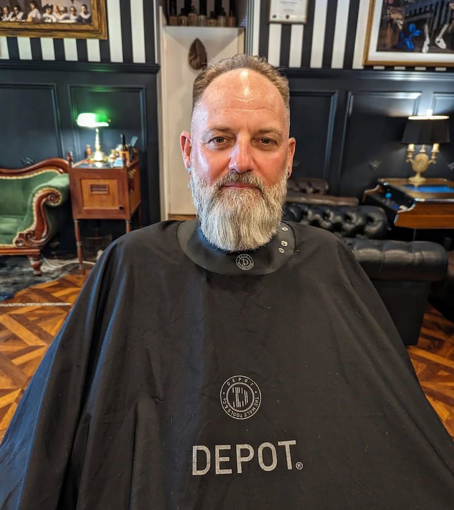 A Man With a Beard is Wearing a Depot Cape — Connolly & Co Barbers In Robina, QLD