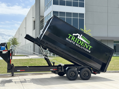 A green dumpster is parked in front of a building.