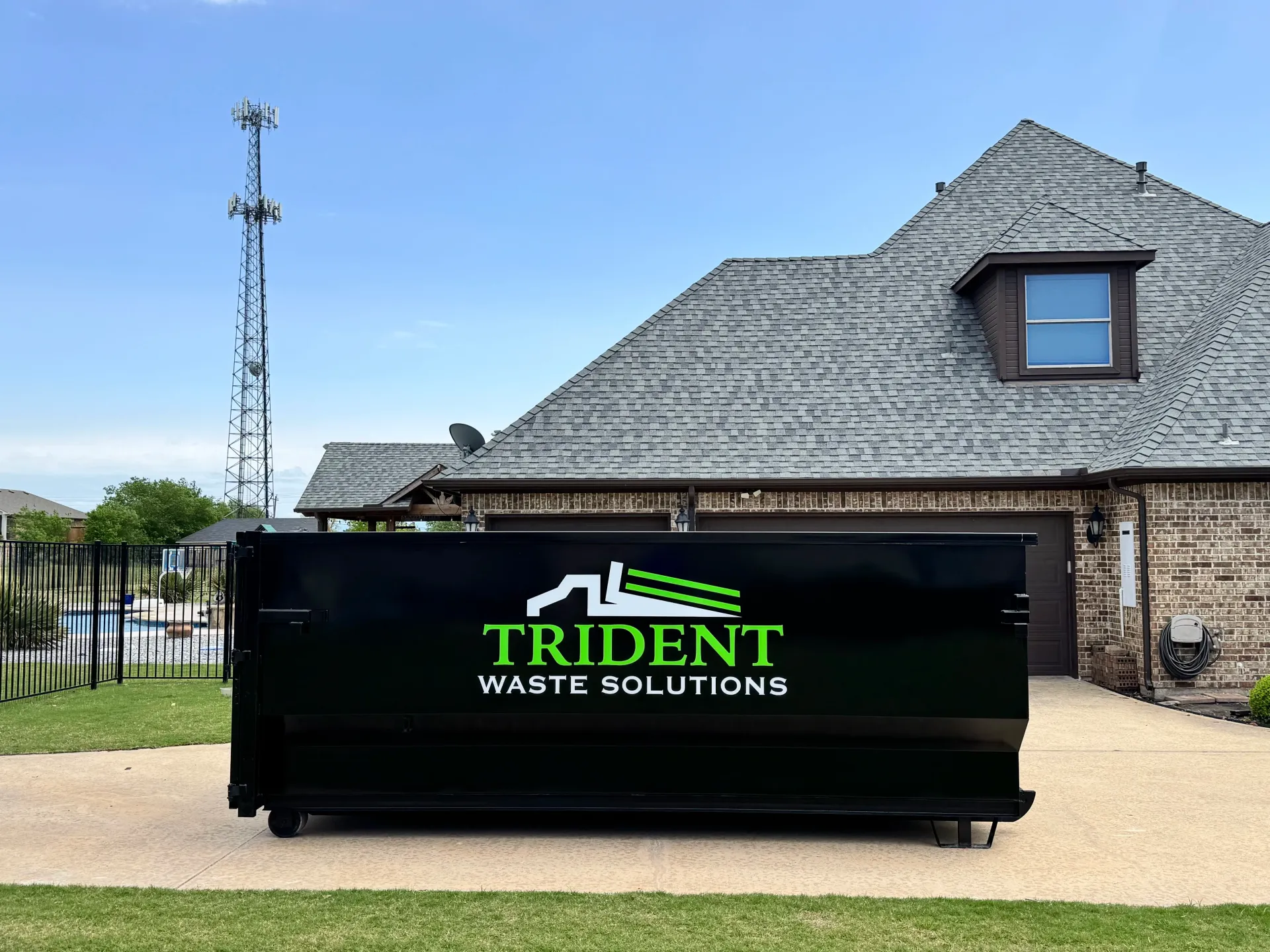 A green dumpster is parked in front of a brick building.