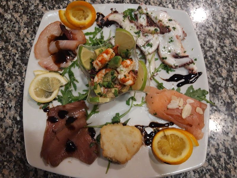 Un piatto bianco con una varietà di pesce sopra