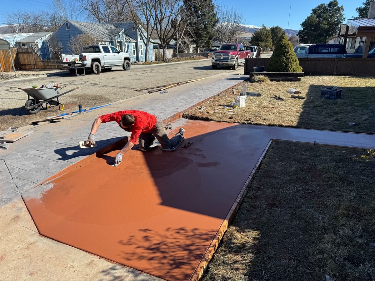 Person painting a large orange surface outdoors in a suburban driveway