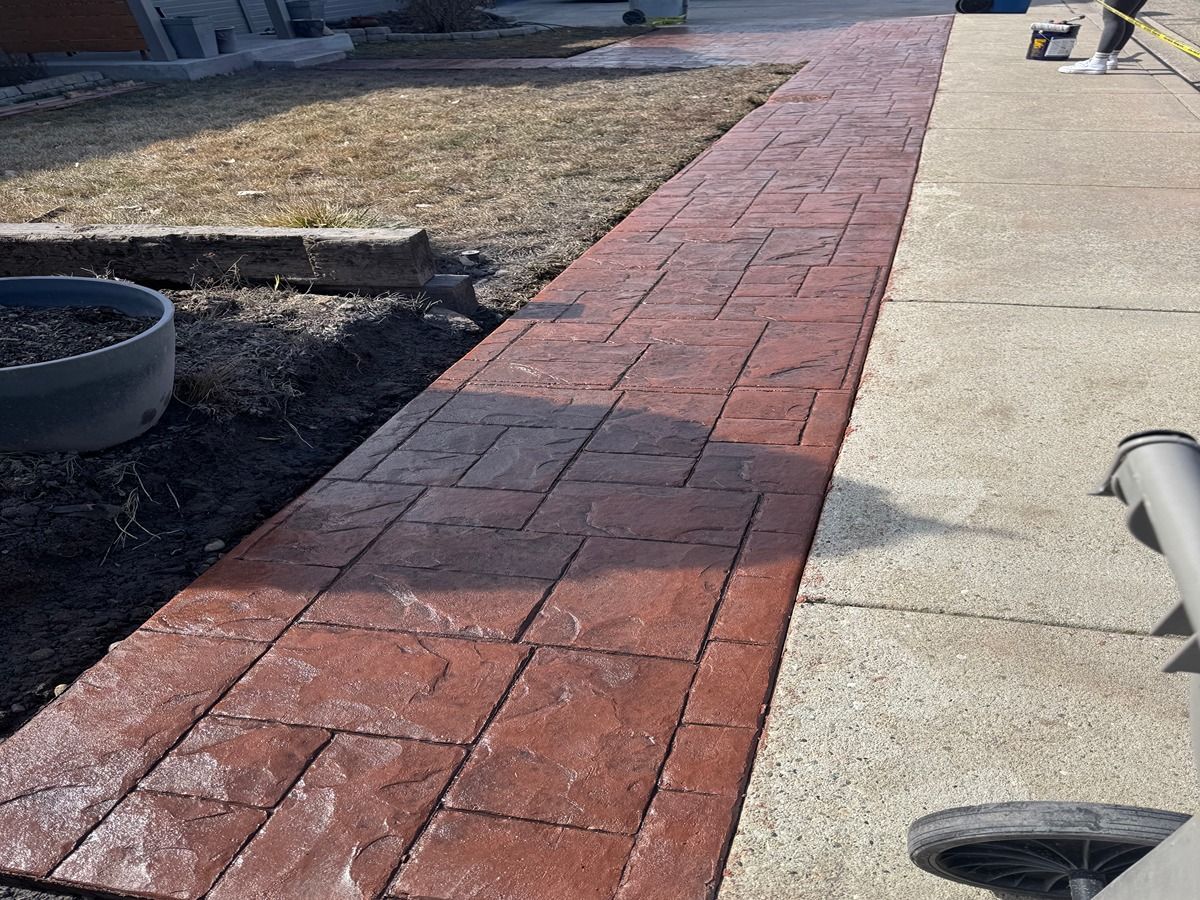 Red brick walkway beside a concrete path and dry lawn in daylight