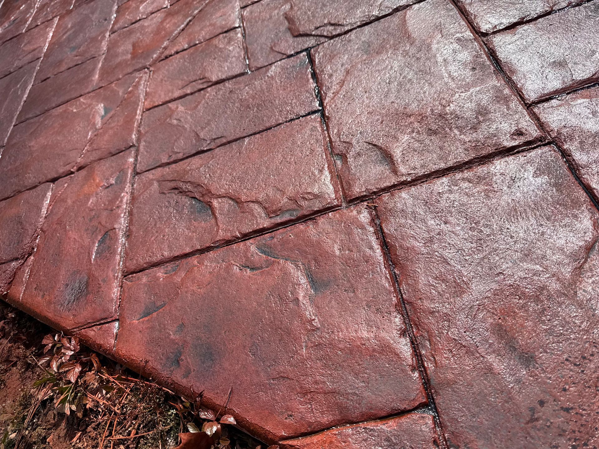 Close-up of cracked red concrete pavers with white residue along the edges