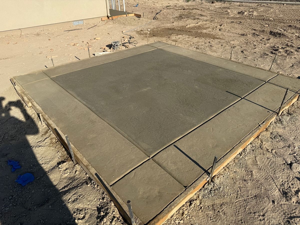 Freshly poured concrete slab in a sandy construction site.
