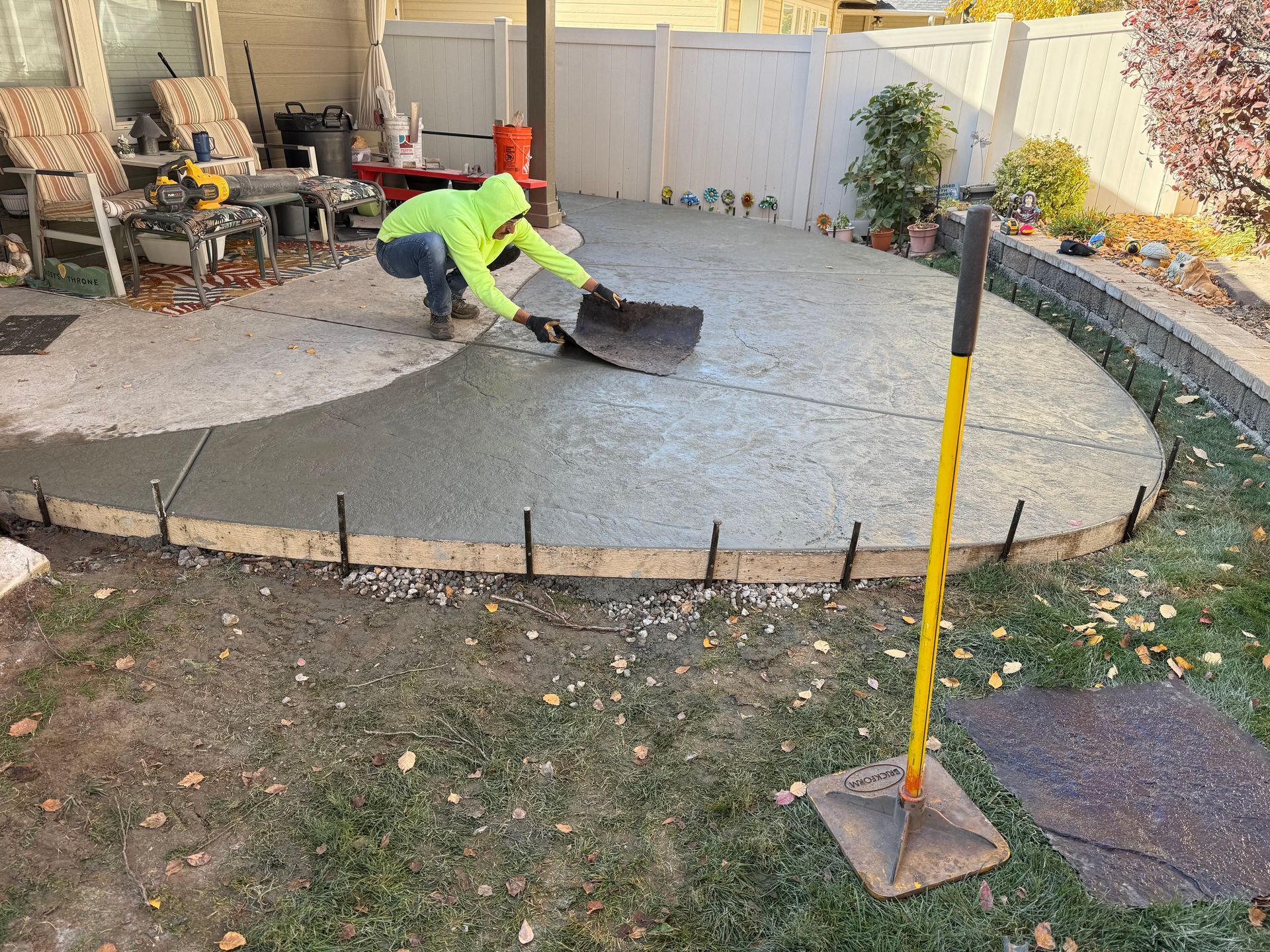 Worker in neon shirt spreading concrete on a backyard patio