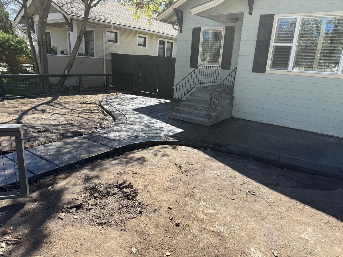 Front yard with a concrete walkway, small front steps, and a light-colored house in the background