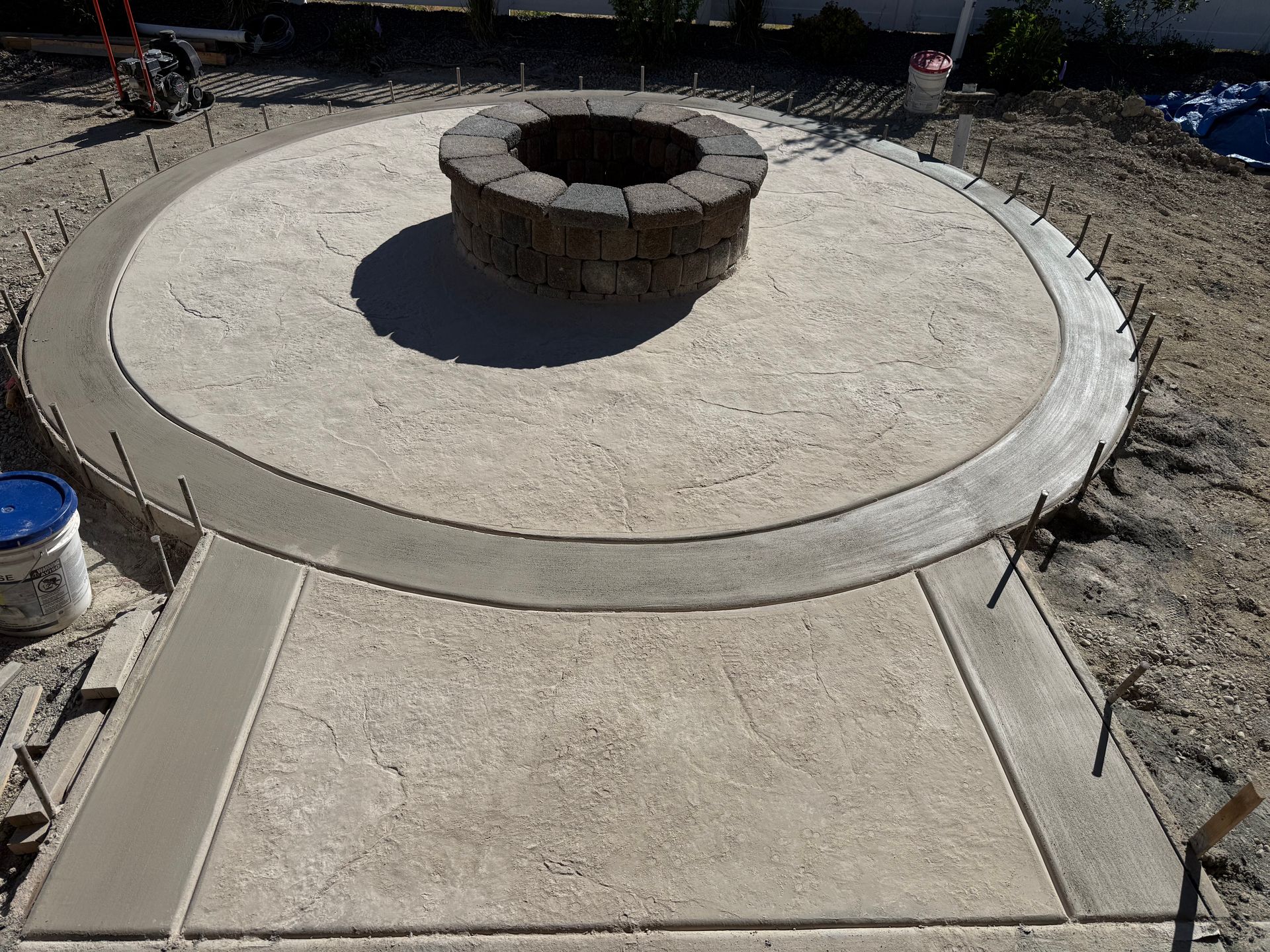 Concrete patio with circular fire pit in a landscaped outdoor area