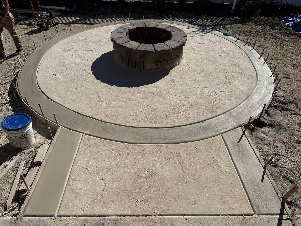Concrete patio with a circular brick fire pit in the center, viewed from above.