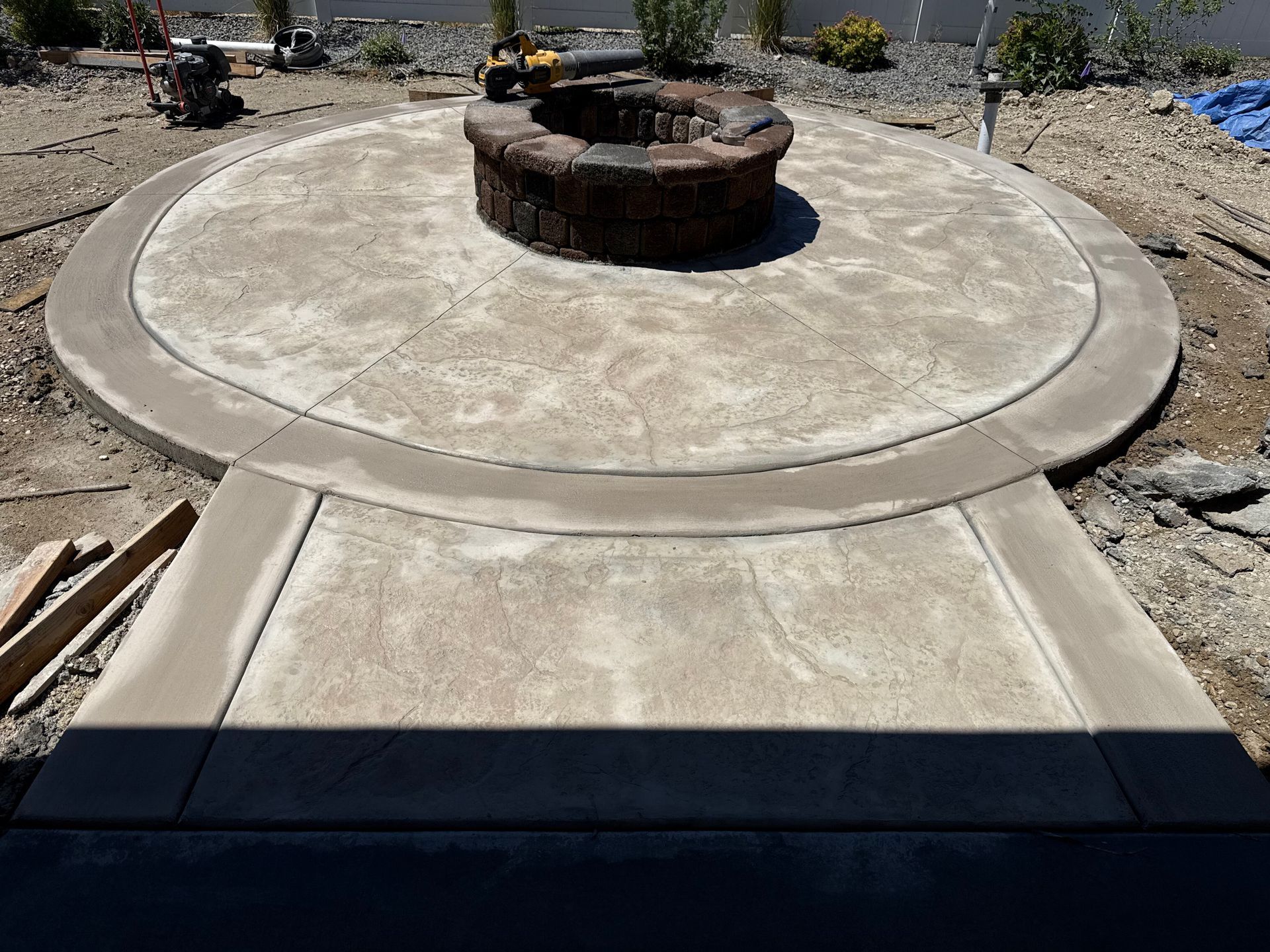 Circular concrete patio with a central round fire pit under construction outdoors
