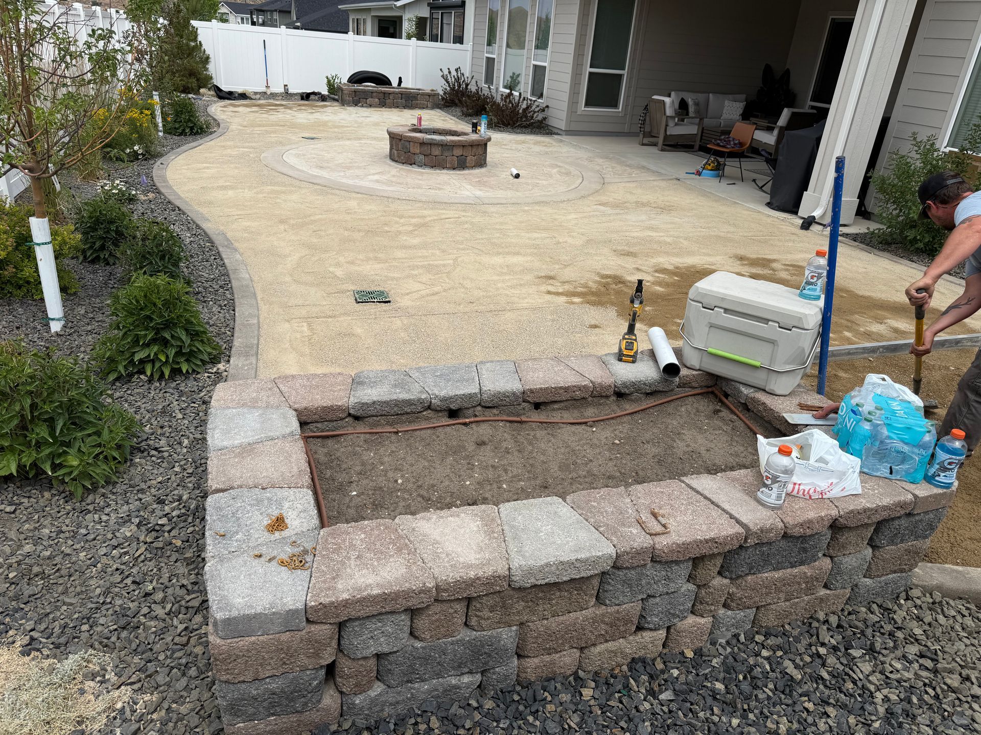 Backyard patio with stone steps, gravel border, and a fire pit in the distance