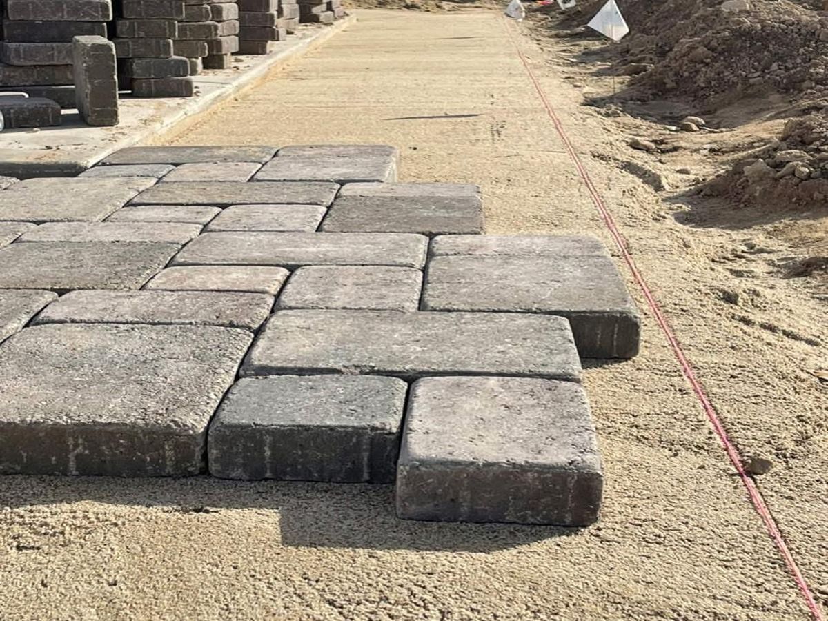 Stone pavers laid on a dirt path at a construction site, with more blocks stacked in the background