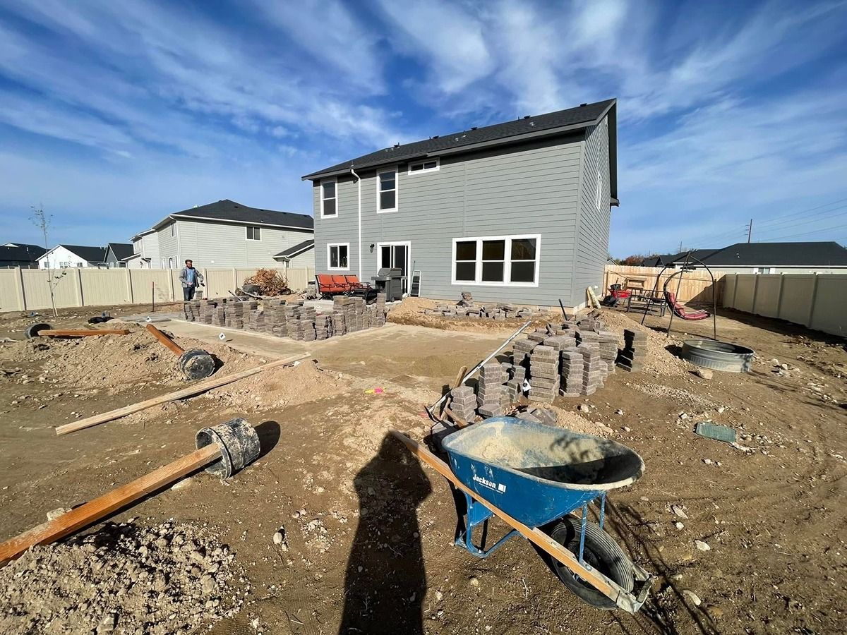 Partially built house at a construction site with dirt, debris, and a blue wheelbarrow in the foreground