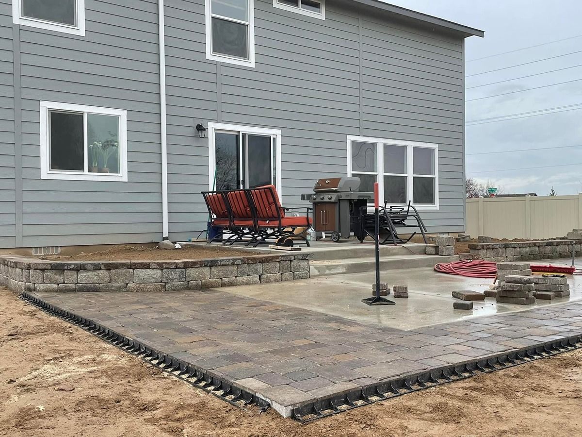 Backyard patio with gray house, concrete seating area, fire pit, and outdoor furniture