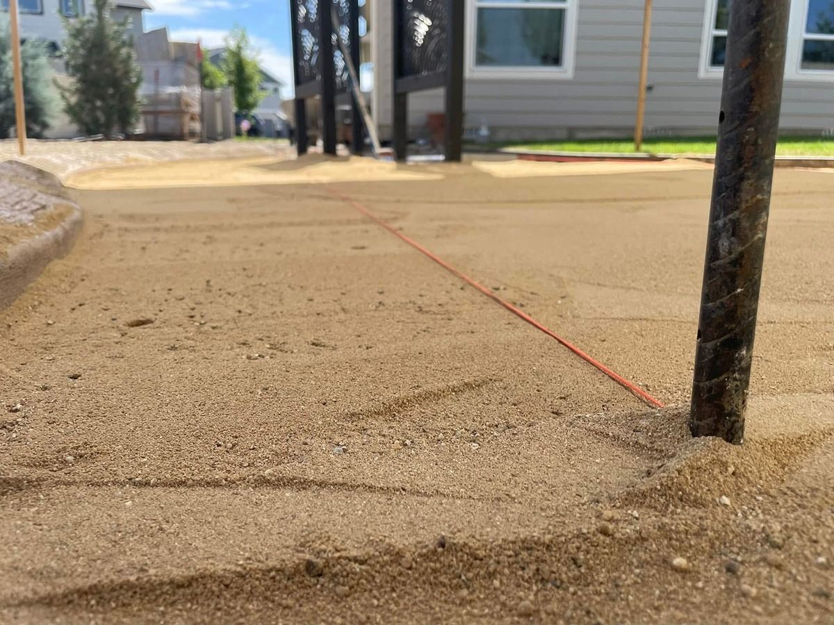 Red chalk line across a sandy sidewalk beside a black pole and apartment buildings.