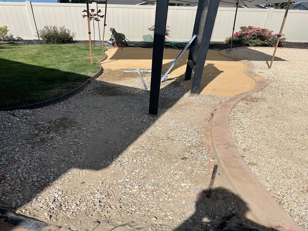 Backyard gravel path with a black swing set and tan stepping stones near a fence.