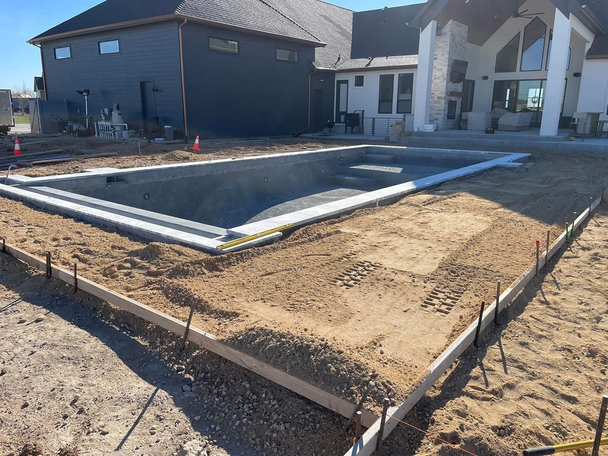 Construction site with foundation forms and gravel in front of a house under construction