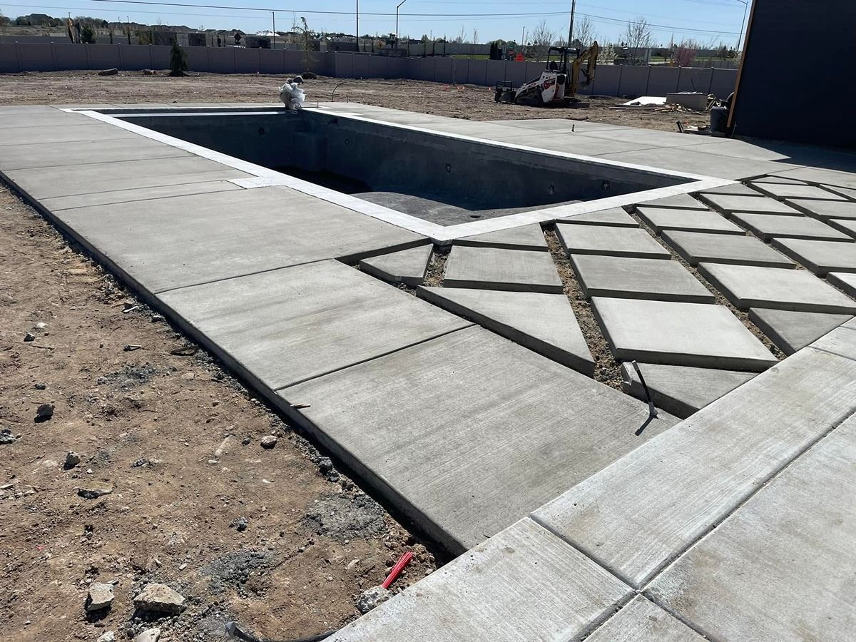 Empty rectangular swimming pool with unfinished concrete deck in a desert lot.