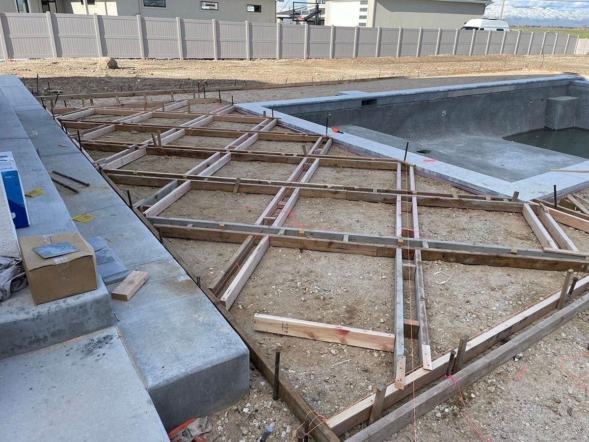 Concrete pool construction with wooden formwork and rebar grid around an empty pool basin