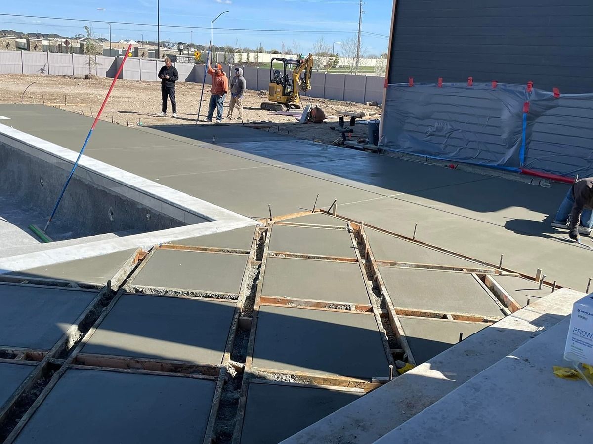 Construction site with concrete slab and workers near a partially installed rebar grid beside a roadway.