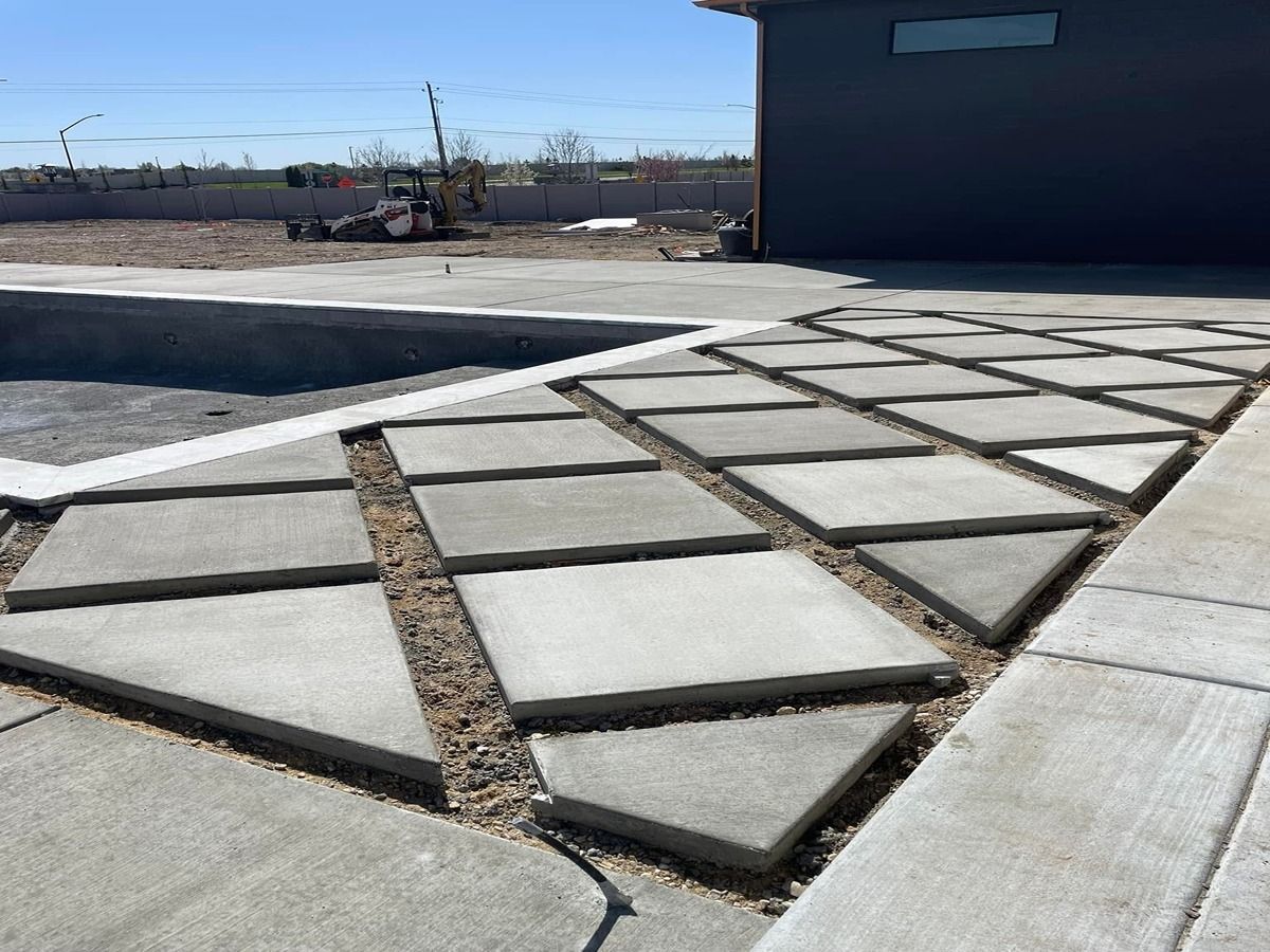 Concrete sidewalk with geometric stepping stones beside a dark building on a sunny day