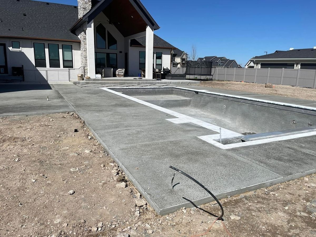 Concrete foundation slab at a house construction site with white framing outlines and gravel beside it