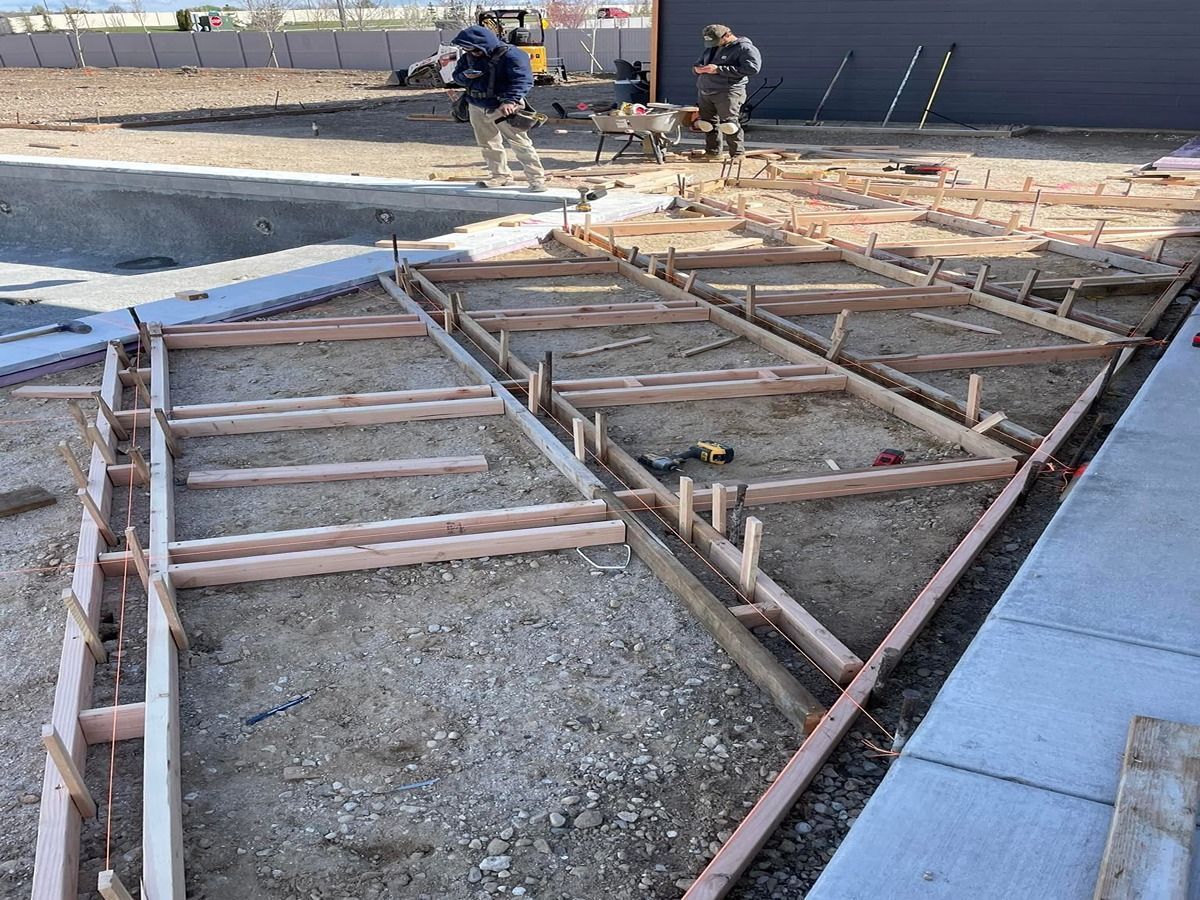 Workers framing a concrete patio foundation with wood forms on a construction site
